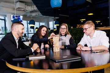 Fototapeta na wymiar Businessmen play jenga. Business holiday concept. Young people play board games in the office