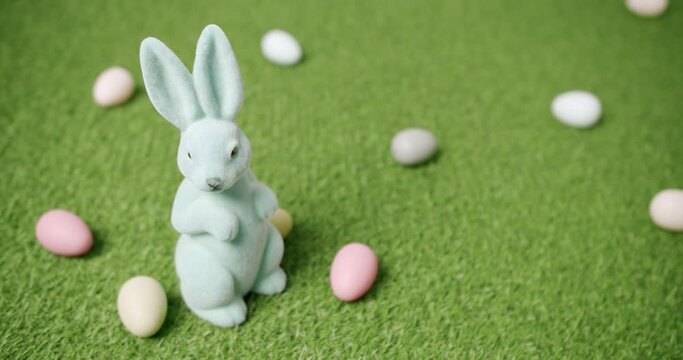 Rabbit toy on a background of green grass with many colored eggs, text messages