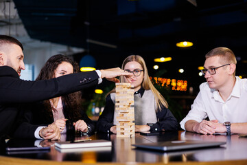 Businessmen are playing Jenga games. They sit in the office and play games. Concept photo for design and work.