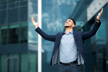 Emotional middle-eastern businessman standing next to office building