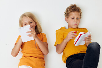 two joyful children drawing in notebooks lying on the floor light background unaltered