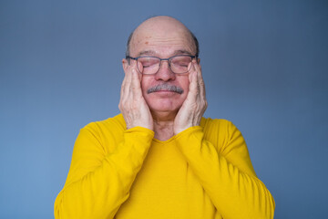 Senior worried man in glasses rubbing eyes being tired