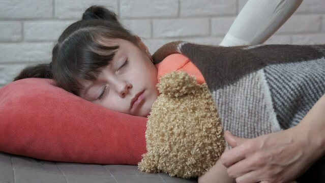 Little girl rest with toy. A child with teddy bear has a rest while her mother cover her with a blanket.