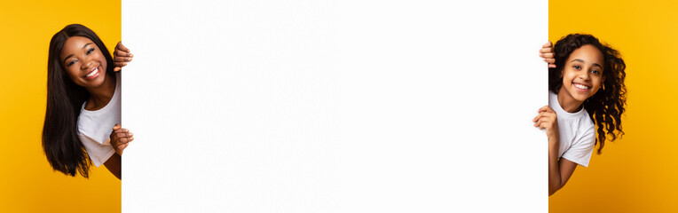 African people peeking out blank white advertising billboard at studio