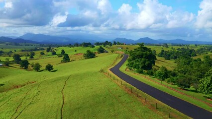 Empty Asphalt Road Through Green Hills At Daytime In Atherton, Tablelands, Australia. - aerial pullback