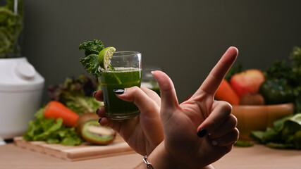 Woman golding glass of green detox vegetable smoothie. Healthy food concept.