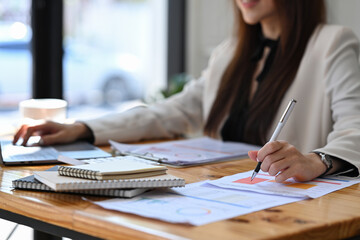 Female accountant working with laptop computer and checking financial document.