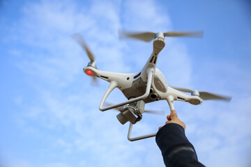 Fototapeta na wymiar Hand reaching a white drone with camera flying against blue sky