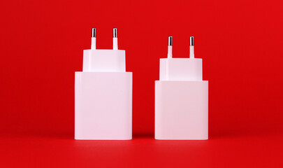 Two white charger power supplies on a red background