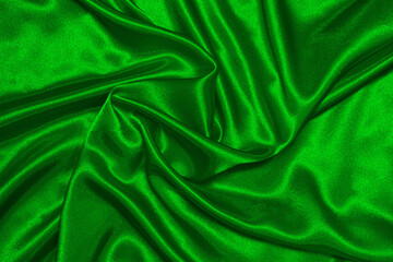 Texture of crumpled green satin fabric, beautiful pattern, top view.