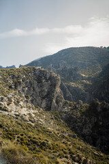 Fototapeta na wymiar Paisaje de la sierra de Granada con tonos verdes y cielo despejado con nubes bajas agregando neblina a la escena 