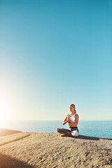 Everyone should practice yoga. Shot of a young woman doing yoga at the beach.