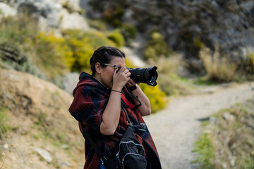 Chica joven guapa tomando fotografías en entorno natural mientras pasa por rutas y puentes...