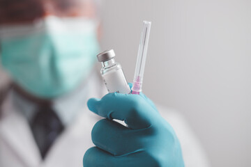 doctor or scientist in the COVID-19 medical vaccine research and development laboratory holds a syringe with a liquid vaccine to study and analyze antibody samples for the patient.
