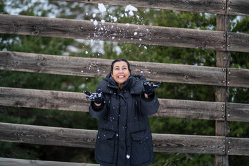 Chica joven guapa en la nieve posando feliz ante la cámara y poniendo caras graciosas