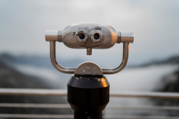 Telescopio en mirador de una montaña frente a paraje natural nevado