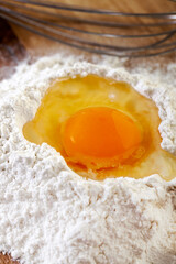 One Egg in Flour with Wisk on Wooden Table Surface