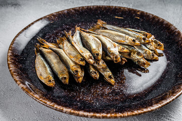Smoked sprat fish in rustic plate. White background. Top view - obrazy, fototapety, plakaty