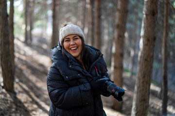 Chica joven guapa en un bosque de arboles altos con cámara de foto colgada al cuello