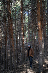 Chico alto con barba y gorro gris en bosque de arboles altos 