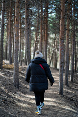 Chica joven guapa en un bosque de arboles altos con cámara de foto colgada al cuello