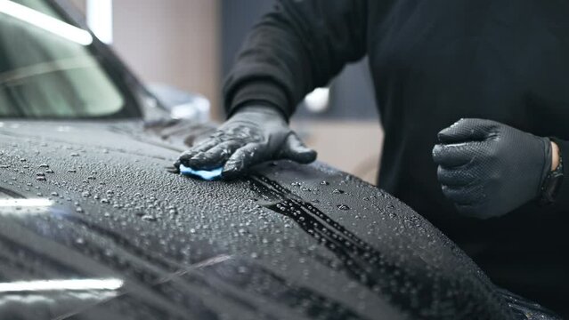 Worker clean car body with blue clay for cleaning before installing protective layer or PPF coating to auto. Car detailing concept