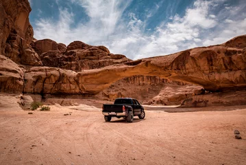 Abwaschbare Fototapete Lachsfarbe A car in view through a rock arch in the desert of Wadi Rum