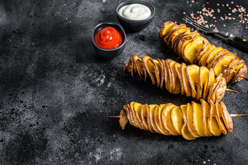 Roasted Tornado or twisted potatoes with ketchup sauce. Black background. Top view. Copy space