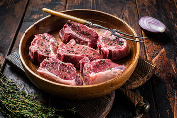Raw lamb loin rib chops steaks in wooden plate with herbs. Wooden background. Top view - obrazy, fototapety, plakaty
