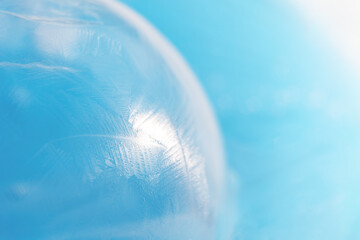Frozen surface of soap bubble against blue background.