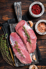 Raw Duck breasts, poultry meat steaks on wooden board ready for cooking. Wooden background. Top view