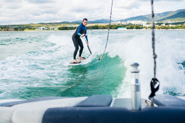 Watersport concept. Young athletic woman learning wakesurfing and perfecting tricks. Female in...