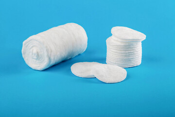 Roll of medical cotton wool and cotton pads on a blue background