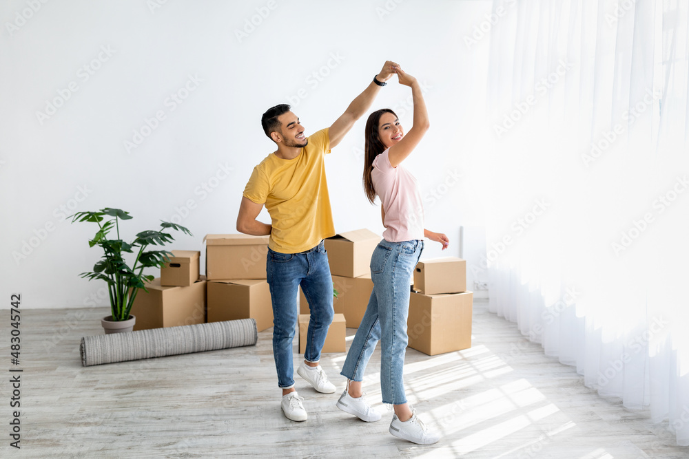 Canvas Prints affectionate multiracial couple dancing in their house among carton boxes on moving day, free space