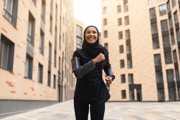 Fototapeta na wymiar Sport For Muslim Women. Islamic Lady In Hijab Running On City Streets