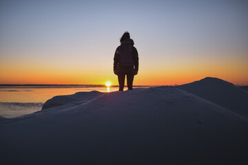 Girl watching sunrise alone at swedish coastline Magical light on a cold morning Time to breathe and clear the mind