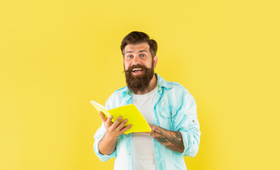 surprised bearded man with book on yellow background, surprise