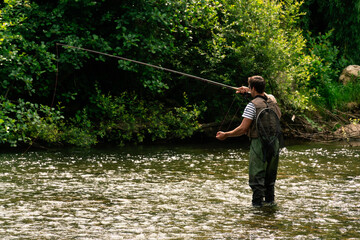 Young man fishing trouts in the river