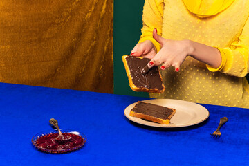 Food pop art photography. Cropped portrait of girl and sweet chocolate toasts on blue tablecloth....