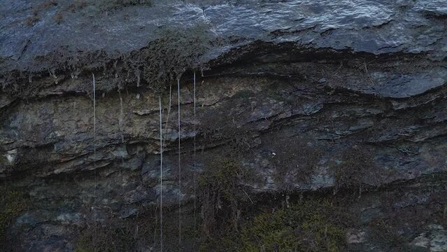 Water flows down the rock Mini waterfall in the rock Moss grows on wet stone Water drops wet rock, close-up Destruction of rocks by water in the mountains