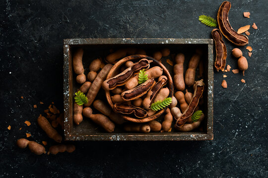 Exotic tamarind fruits in a box. Top view. On a stone background.