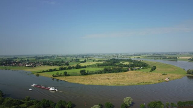 Ship on the river IJssel with high water level on the floodplains near the city of Zwolle in Overijssel during summer after heavy rainfall upstream. Aerial drone point of view.