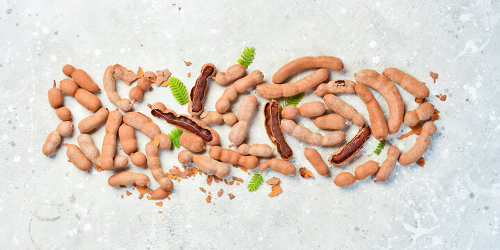Fresh Tamarind (Tamarindeiro) tropical fruits with leaf. On a gray stone background.