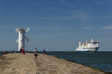 SEA COAST LANDSCAPE - Holiday tourists are walking on the breakwater and passenger ferry sail to...