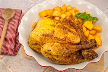 whole roasted chicken with potatoes in a dish on a table 