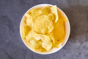 A white bowl with french fries on a black slate background