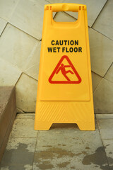 Wet floor sign board beside wooden stairs at swimming pool