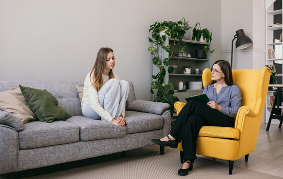 a depressed woman patient is sitting on the couch telling a psychologist about problems. Professional psychological assistance