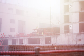 Multi-storey house construction process, builders are building a residential building on a foggy...