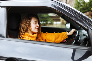 Portrait of young beautiful woman in yellow sweater sitting in the car.